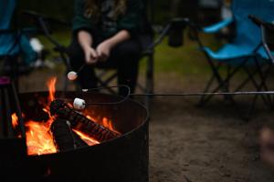una persona asando malvaviscos sobre un fuego en Sweet Grass - Tipi 1, en New Braunfels