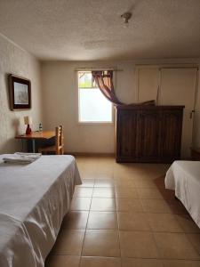 a bedroom with two beds and a table and a window at Anys Hostal in Mexico City