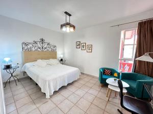 a bedroom with a white bed and two chairs at Nice apartment Duque Tenerife South in Adeje