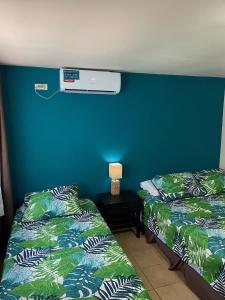Habitación con 2 camas junto a una pared azul en Uverito Sand Dollar B&B, en Las Tablas