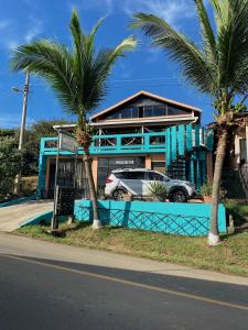 a car parked in front of a house with palm trees at Uverito Sand Dollar B&B in Las Tablas