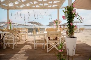 a restaurant on the beach with tables and chairs and flowers at Hotel Roxy & Beach in Cesenatico
