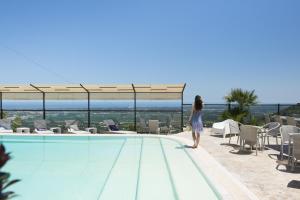 a woman standing on the edge of a swimming pool at Al Mirador Resort in Selva di Fasano
