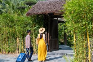 un hombre y una mujer caminando por un camino con una maleta en Tam Coc Retreat Ninh Binh en Ninh Binh
