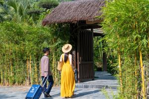 a man and a woman walking down a path with a suitcase at Tam Coc Retreat Ninh Binh in Ninh Binh