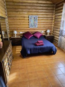 Un dormitorio con una cama con sábanas y almohadas púrpuras. en Gran Cabaña Falaguera en Bárig