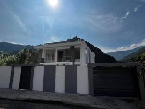 a white house with a black and white garage at Moderna casa vacacional en Baños in Juivi