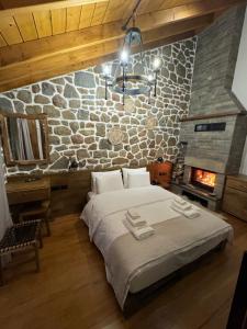 a bedroom with a large bed and a stone wall at Hotel Ambassador Voskopojë in Voskopojë