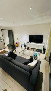 a living room with a black couch and a tv at Trendy & Chic Apartment In The Heart of London in London