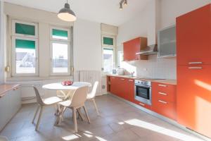 eine Küche mit roten Schränken sowie einem Tisch und Stühlen in der Unterkunft ALTIDO Trendy units in the city centre in Triest