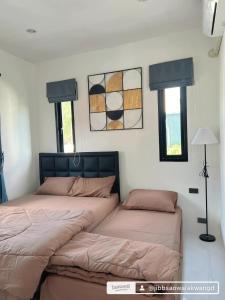 two beds in a bedroom with two windows at B.leaf villa บีลีฟ วิลล่า in Cha Am