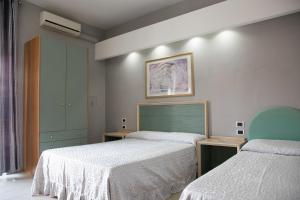 a bedroom with two beds and a painting on the wall at Maximo Hotel in Tivoli Terme