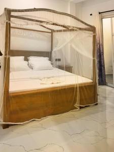1 dormitorio con cama con dosel y sábanas blancas en Golden Wave en Ahangama