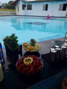 einen Tisch mit zwei Schalen Obst neben einem Pool in der Unterkunft Sítio Meu Refúgio in Cabo Frio