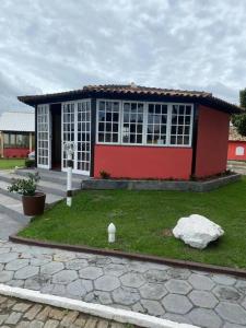 ein kleines rotweißes Gebäude mit einem Rasenplatz in der Unterkunft Sítio Meu Refúgio in Cabo Frio