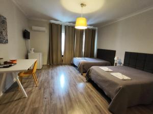 a room with two beds and a table and a desk at Residencial Centro Comercial Avenida Bragashopping in Braga