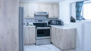 een keuken met witte kasten en een fornuis met oven bij Lovely 1-BR W Sofa Bed in The Heart of NDG in Montreal