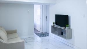 a white living room with a television and a chair at Lovely 1-BR W Sofa Bed in The Heart of NDG in Montréal