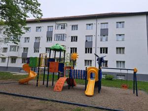 un parque infantil frente a un gran edificio en Anne Studio, en Onești