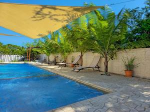 una piscina con sillas y palmeras junto a una pared en Villa Juliana Monterrico, en Taxisco