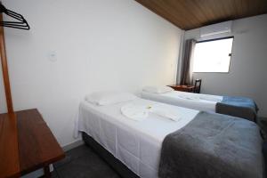 two beds in a room with a window at Pousada Girassol in Maceió