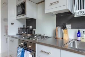 a kitchen with white cabinets and a stove top oven at Spacious 4 bed, Central Camden in London