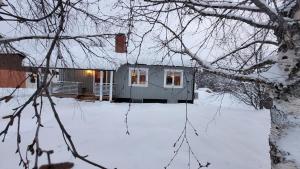 una pequeña casa en la nieve con un patio cubierto de nieve en Enjoy life Föllinge, en Föllinge