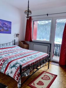 a bedroom with a bed and two windows at Casa Isotta Sappada in Sappada