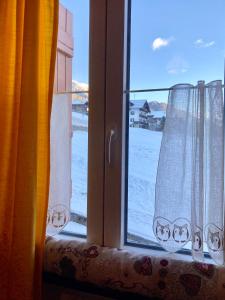 a window with two curtains with a view of snow at Casa Isotta Sappada in Sappada