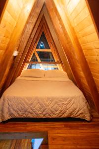 Bett in einem kleinen Zimmer mit Fenster in der Unterkunft CABAÑAS ALPINA in San Agustín
