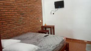 マゲランにあるHomestay Pelangiのベッドとレンガの壁がある寝室