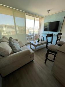 a living room with a couch and a tv and a table at Arriendo Departamento 10 Norte Viña del Mar in Viña del Mar