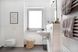 Baño blanco con aseo y lavamanos en Schicke Apartments in Osnabrück I private Parkplätze I home2share en Osnabrück