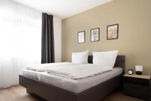 Schlafzimmer mit einem Bett mit weißer Bettwäsche und einem Fenster in der Unterkunft Schicke Apartments in Osnabrück I private Parkplätze I home2share in Osnabrück