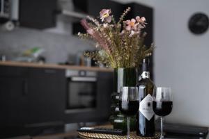 a table with two glasses of wine and a vase of flowers at Schicke Apartments in Osnabrück I private Parkplätze I home2share in Osnabrück