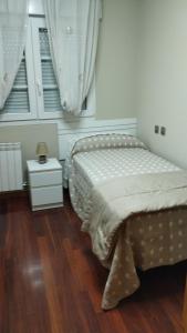 1 dormitorio con 1 cama y suelo de madera en Grupo Arcanos Las Palmeras, en Caldas de Reis