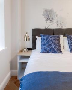 a bedroom with a bed with blue and white pillows at Bright One Bedroom Flats near Marble Arch and Hyde Park in London