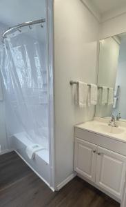 a white bathroom with a shower and a sink at Inn 32 in North Woodstock