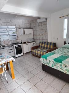uma sala de estar com 2 camas e uma cozinha em Casas do juju em Palhoça