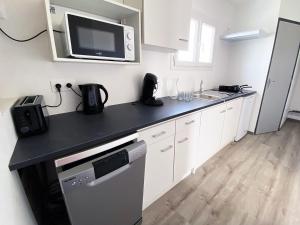 a kitchen with white cabinets and a black counter top at Auberge des Plaines - Appartements avec terrasse in Arles