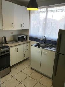 a kitchen with white cabinets and a sink and a window at Arriendo de verano, La Serena 2026 in La Serena +8 photos