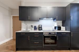 a kitchen with black cabinets and a microwave at Bright One Bedroom Flats near Marble Arch and Hyde Park in London