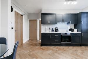 a kitchen with black cabinets and a glass table at Bright One Bedroom Flats near Marble Arch and Hyde Park in London