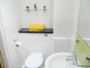 La salle de bains est pourvue de toilettes, d'un lavabo et d'une serviette jaune. dans l'établissement Modern Stylish Apartments and Rooms at Student Roost Corner House in Sheffield, à Sheffield