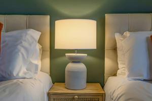 a lamp sitting on a night stand between two beds at Stylish City Centre Apartment with Free Parking, Fast W-fi, Smart TV and Balcony by Yoko Property in Chelmsford