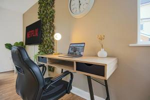a desk with a laptop and a chair in a room at Stylish City Centre Apartment with Free Parking, Fast W-fi, Smart TV and Balcony by Yoko Property in Chelmsford