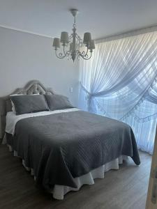 a bedroom with a bed with a chandelier and a window at Arriendo Departamento 10 Norte Viña del Mar in Viña del Mar