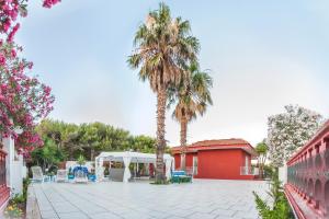 un patio con 2 palmeras y un edificio rojo en Villa Gisella, en Punta Prosciutto