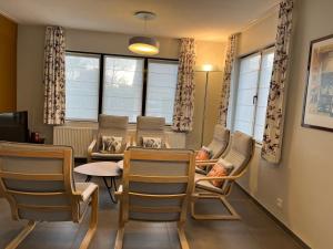 salon z krzesłami, stołem i oknami w obiekcie Villa KARIN w mieście Oostduinkerke