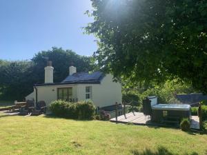 een klein wit huis met een terras in de tuin bij Clotted Cream Cottage: Countryside calm: Close to beach: Dartmouth: Devon in Dartmouth